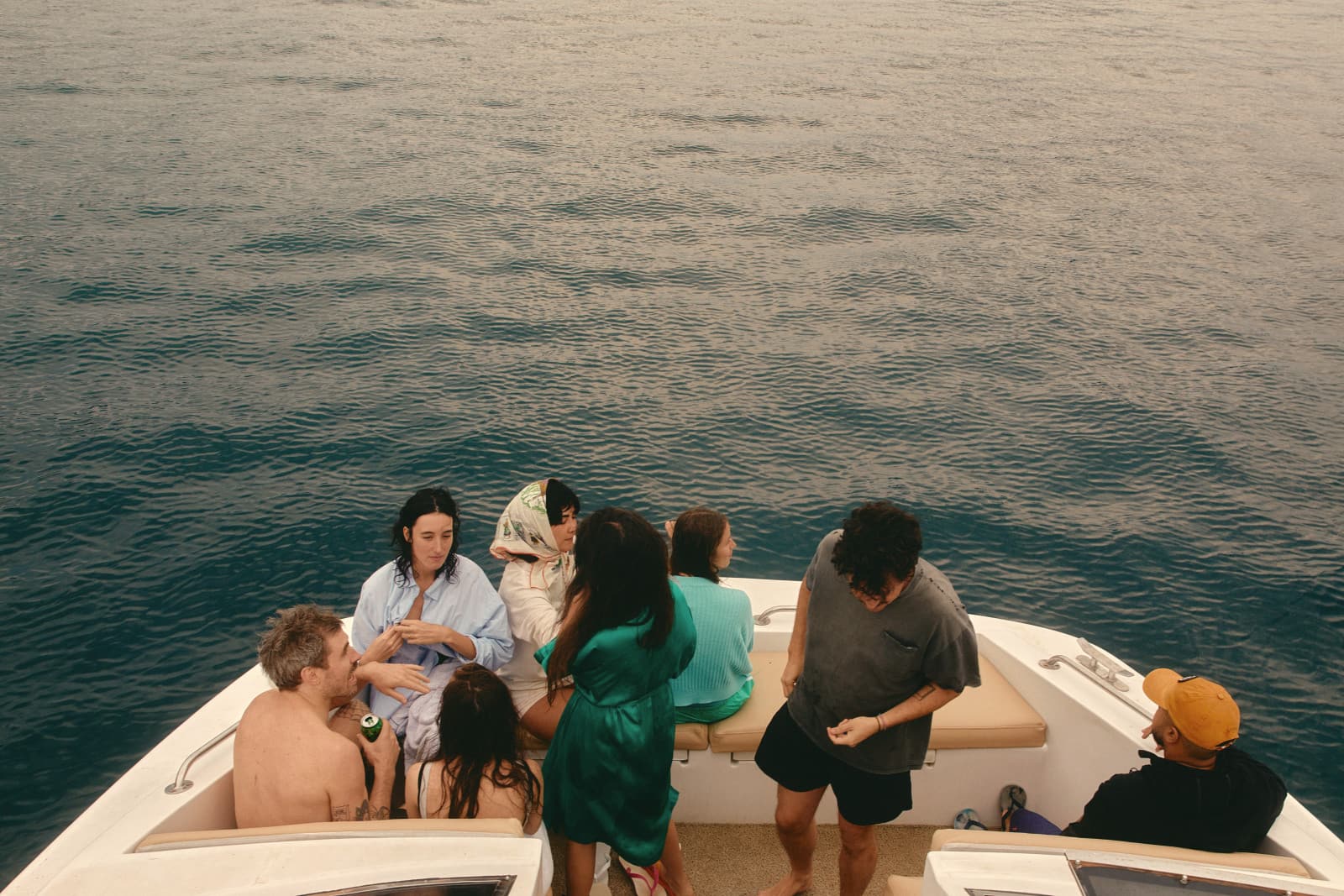 Friends talking on the bow of a boat, deep blue water all around