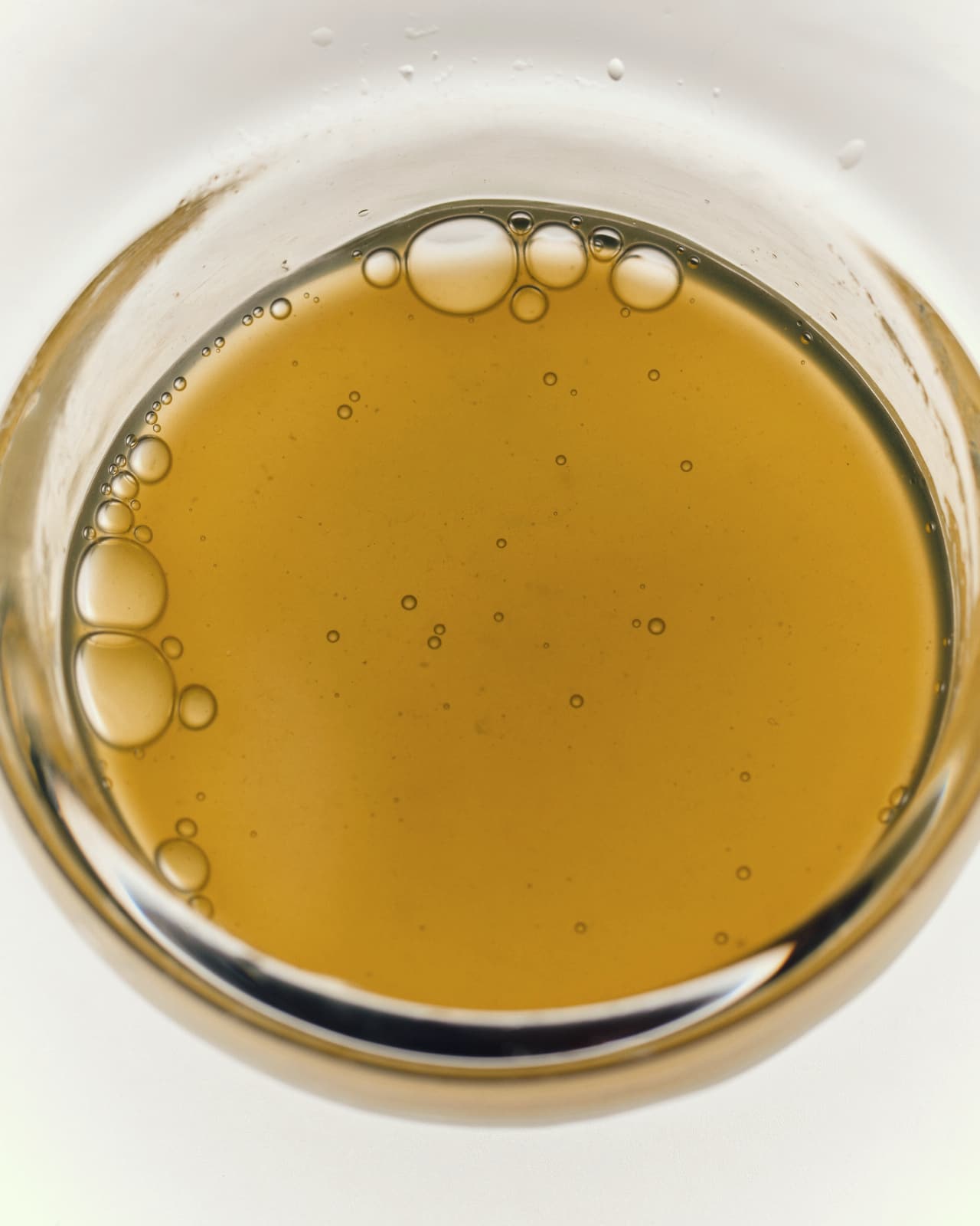 A golden oil in a glass dish, seen from above