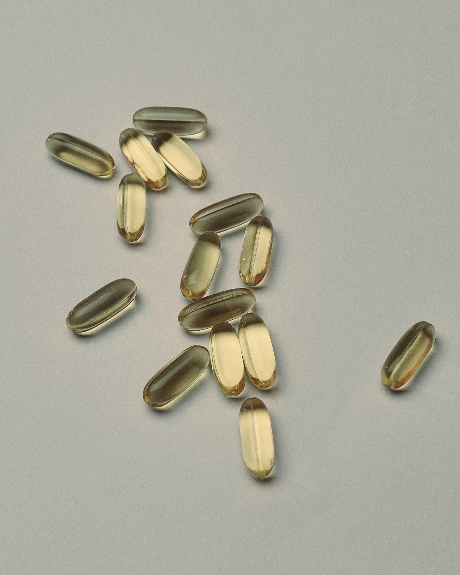Golden softgel capsules scattered on a grey surface