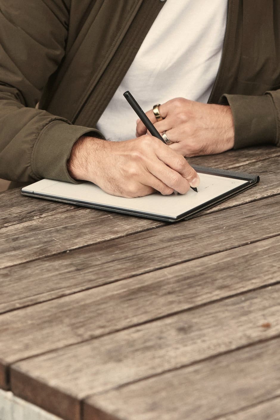 A hand writing in a notebook on the table, pen in hand