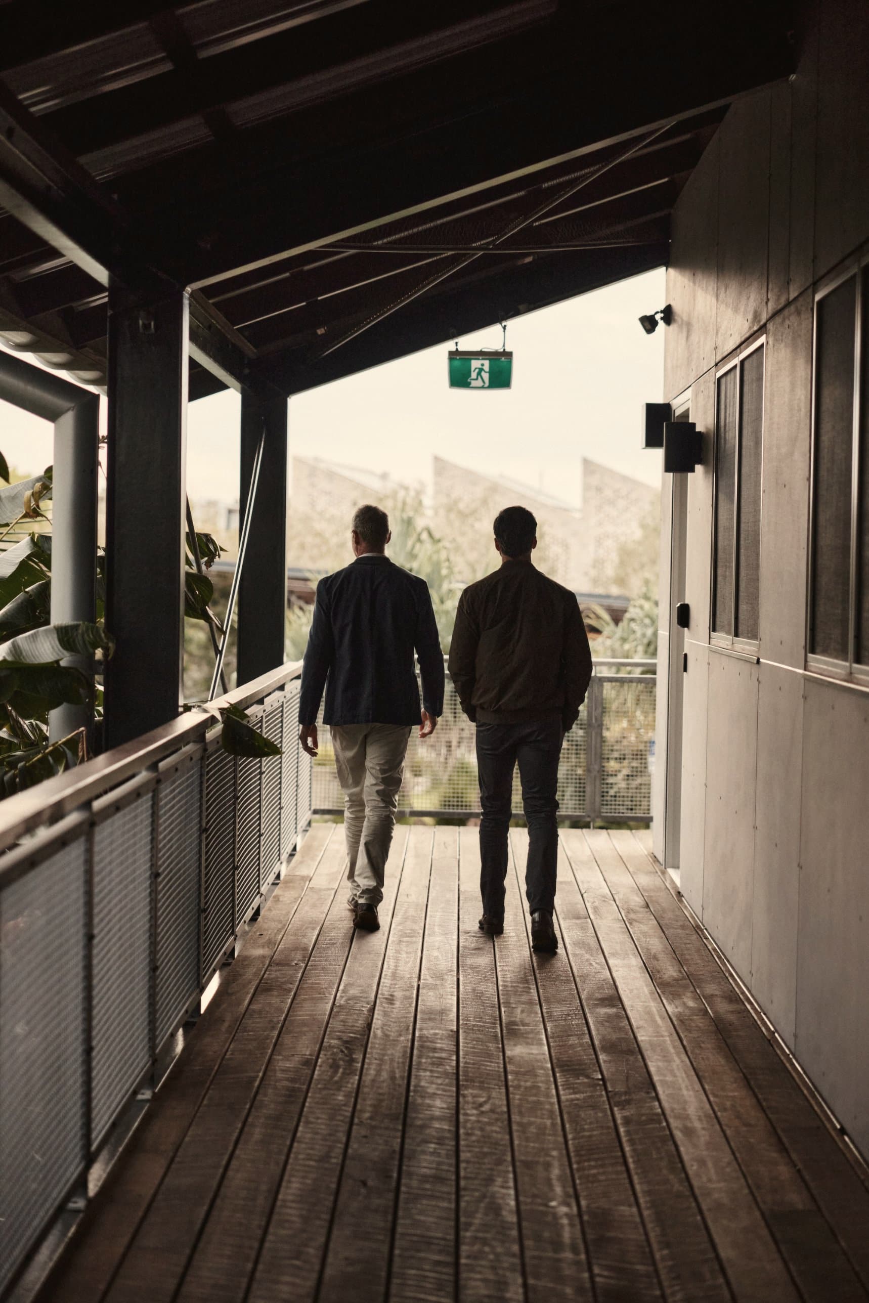 Gabriel Perera and a colleague walking along a covered walkway, seen from behind